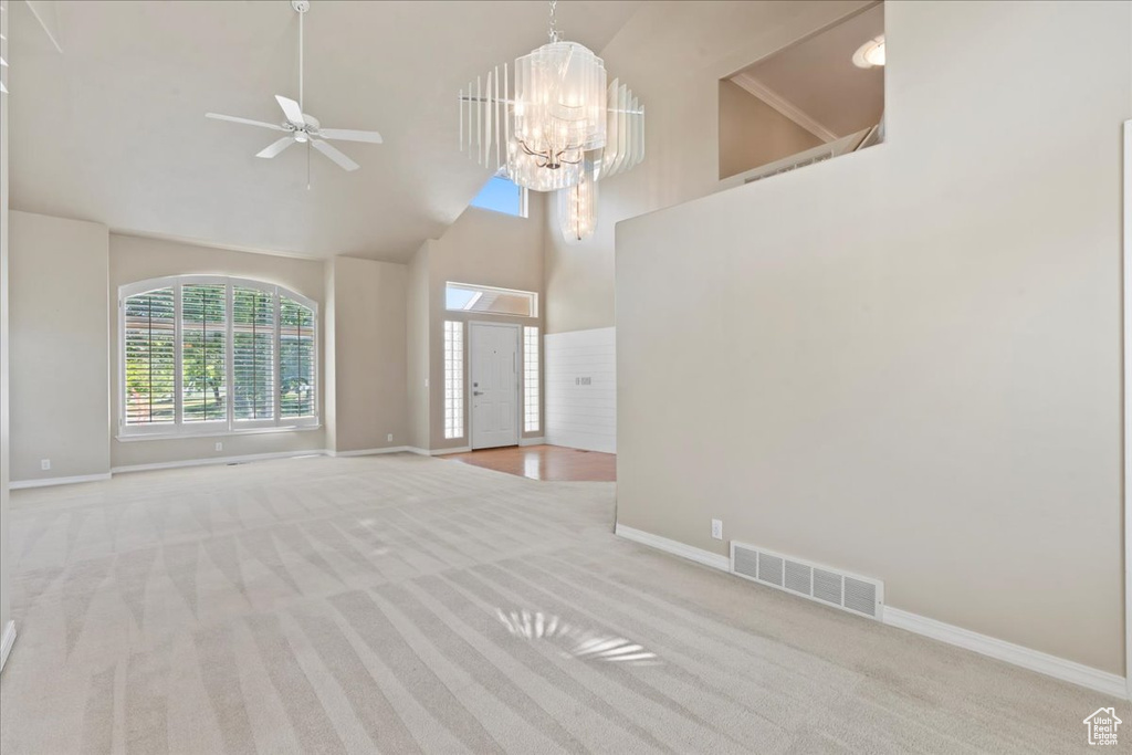 Unfurnished living room with carpet flooring, plenty of natural light, high vaulted ceiling, and a ceiling fan