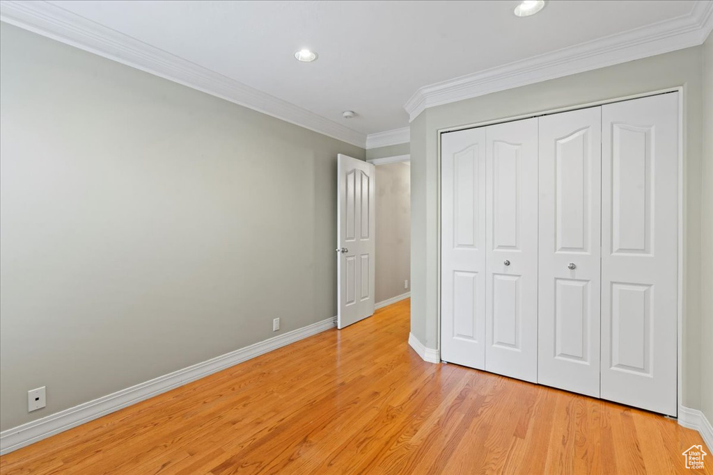 Unfurnished bedroom with light wood-style floors, crown molding, a closet, and recessed lighting