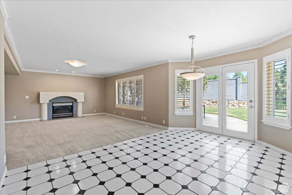 Unfurnished living room with light flooring, light colored carpet, crown molding, and a fireplace with flush hearth