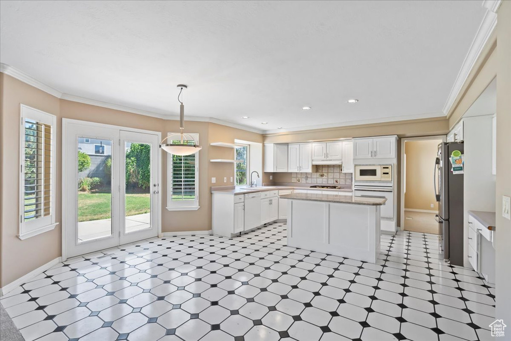 Kitchen featuring white appliances, crown molding, white cabinetry, light floors, and a kitchen island