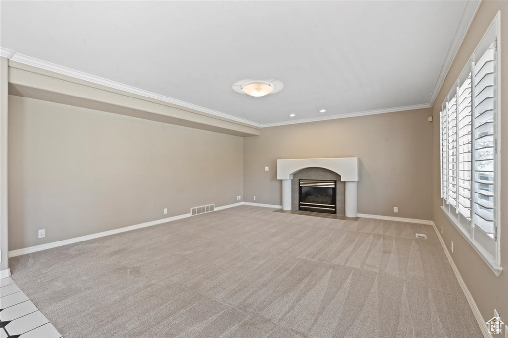 Unfurnished living room featuring ornamental molding, a fireplace with flush hearth, and carpet floors