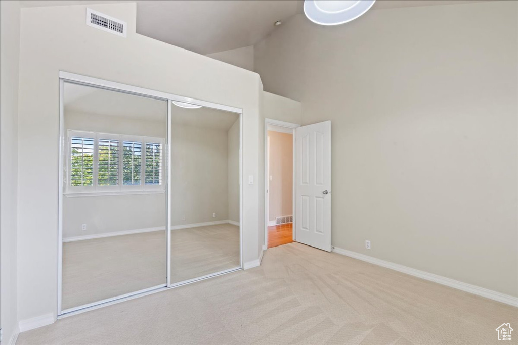 Unfurnished bedroom with carpet flooring, a closet, and a high ceiling