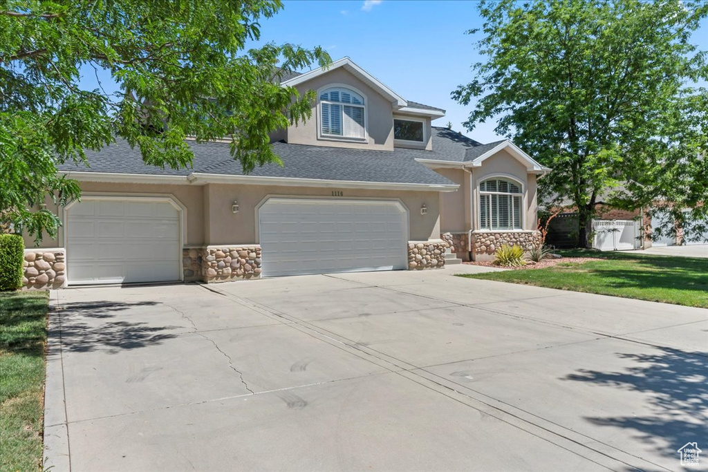 View of front of house featuring stone siding, stucco siding, and driveway
