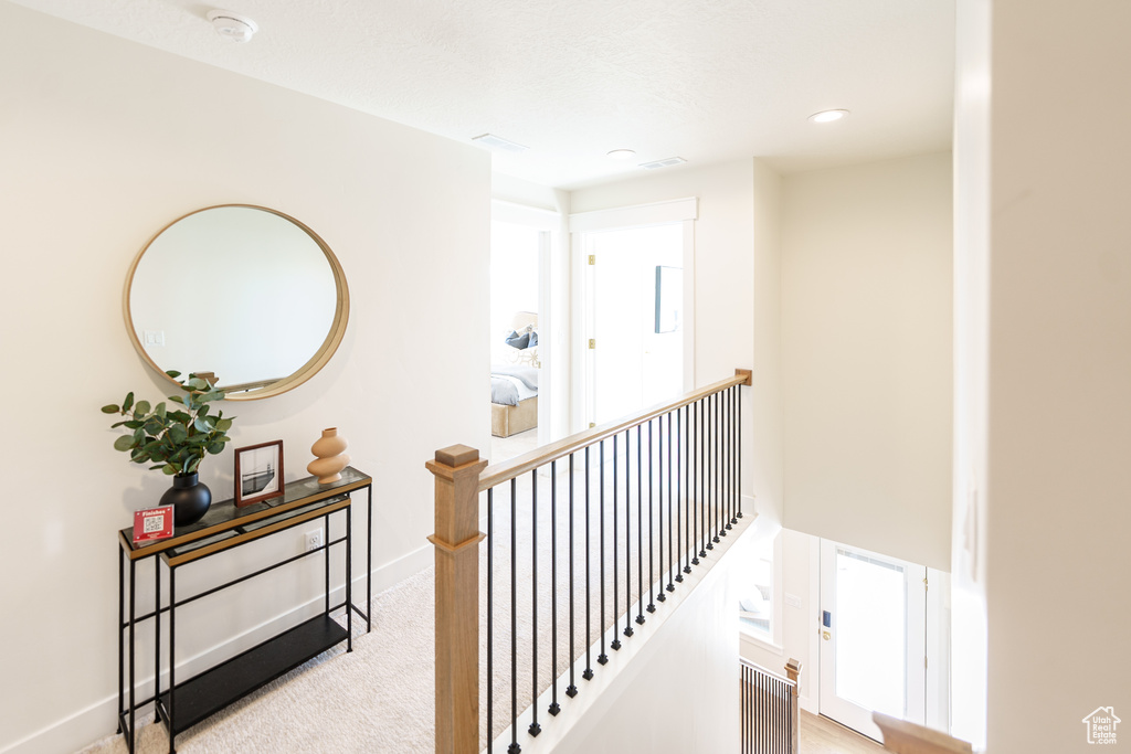 Hallway with an upstairs landing, carpet, and recessed lighting