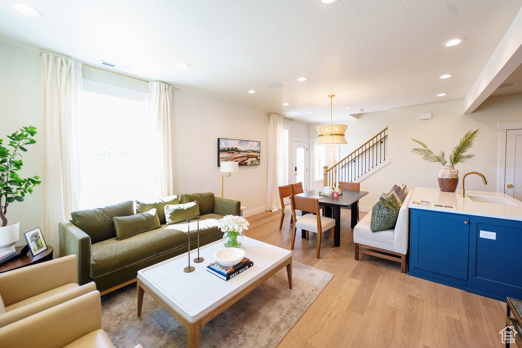 Living room with light wood-style flooring, stairway, and recessed lighting
