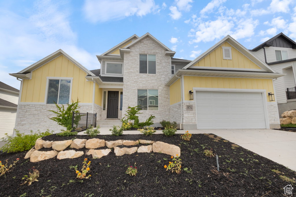 Craftsman inspired home with stone siding, board and batten siding, driveway, and a garage