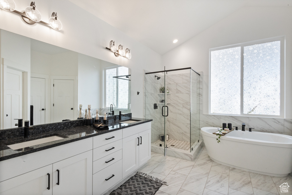 Bathroom with vaulted ceiling, double vanity, a freestanding bath, a stall shower, and marble finish flooring