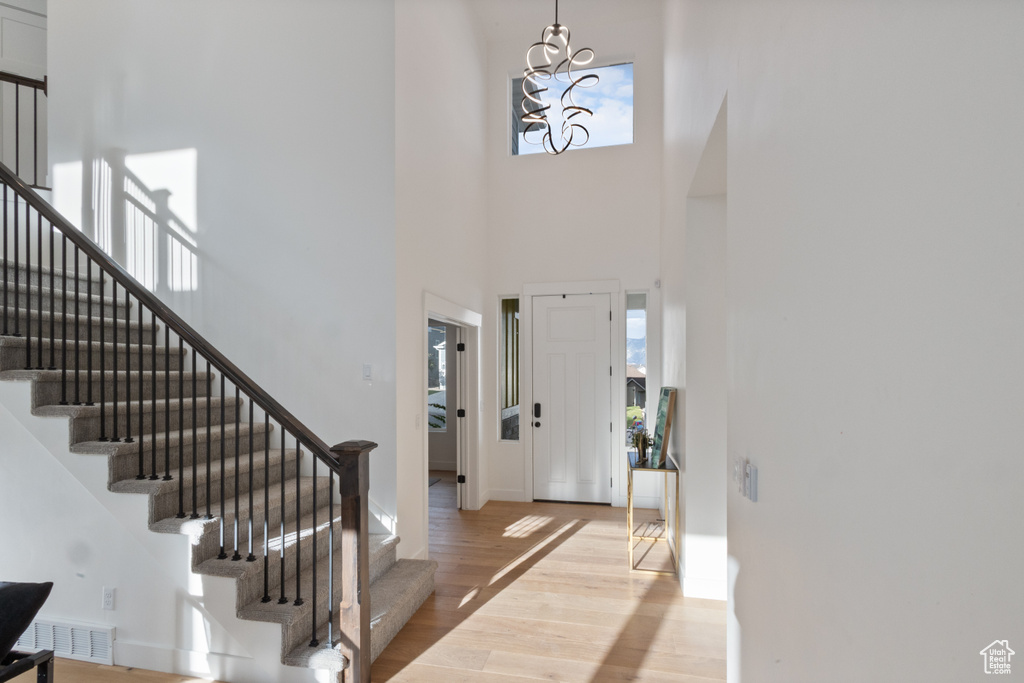 Entrance foyer featuring a high ceiling, plenty of natural light, stairs, light wood-type flooring, and a chandelier