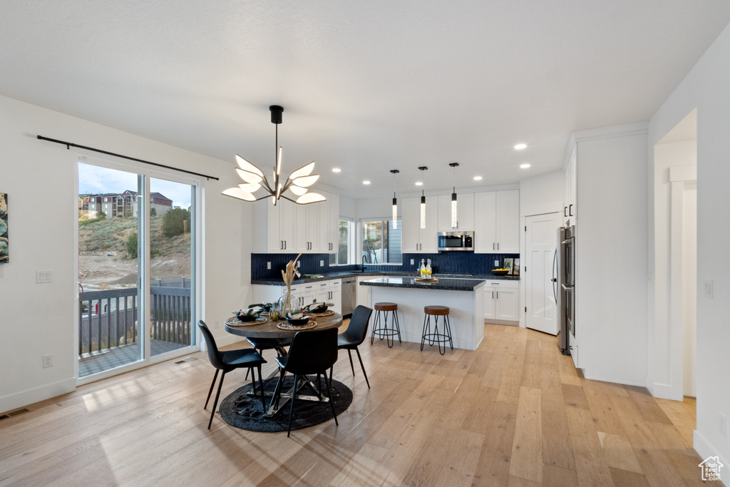 Dining area featuring light wood finished floors, a chandelier, and recessed lighting