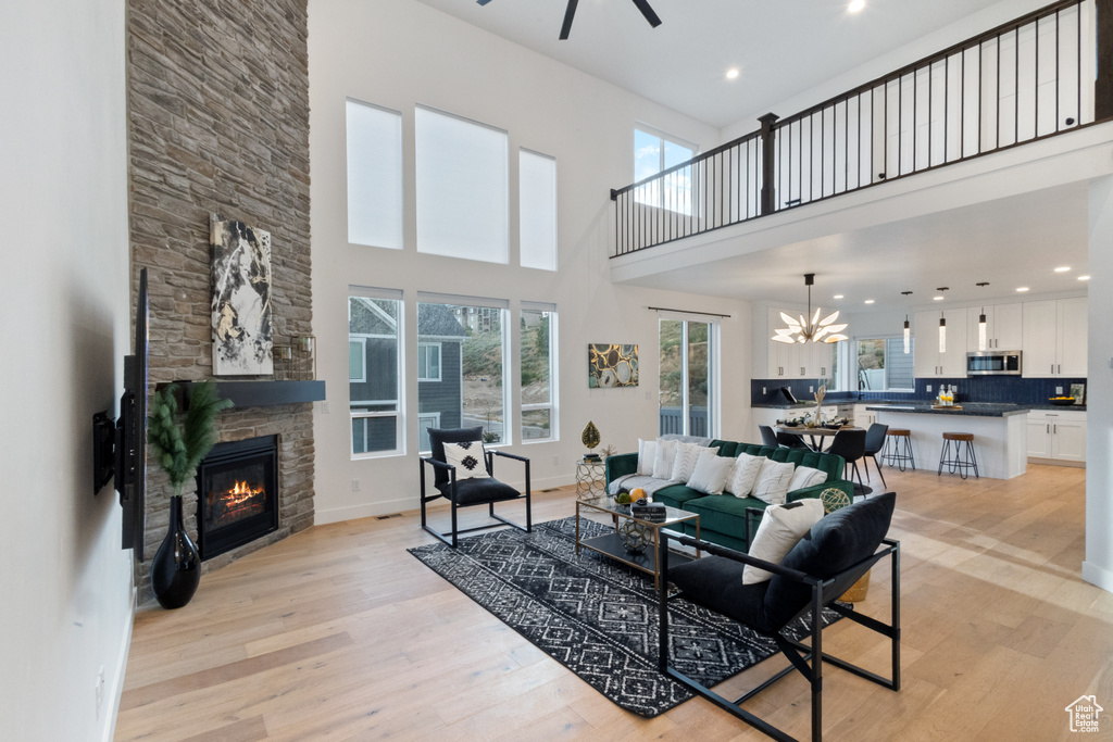 Living area featuring a fireplace, a ceiling fan, light wood-style flooring, a high ceiling, and recessed lighting