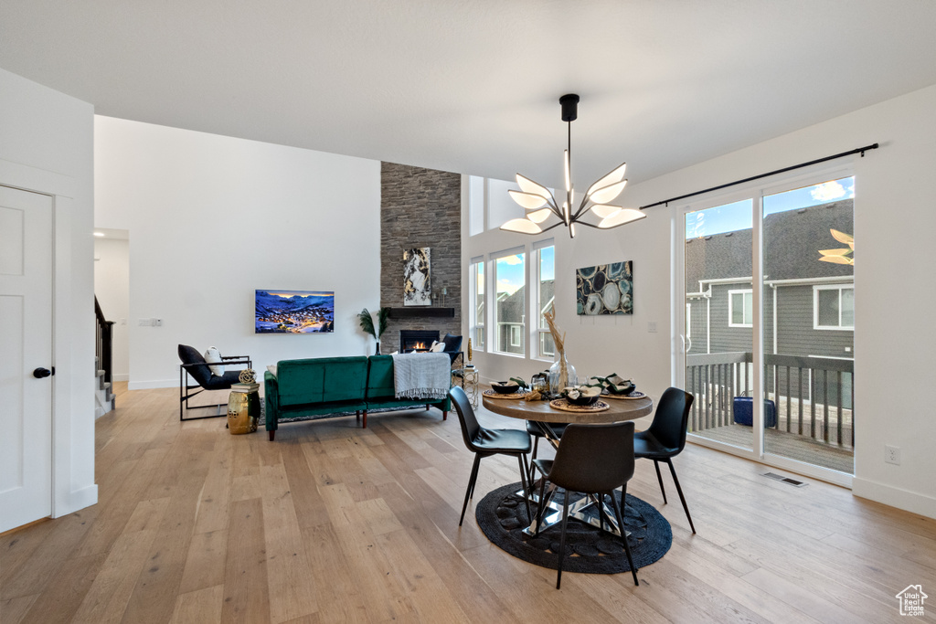 Dining area with a chandelier, a fireplace, and light wood-style flooring