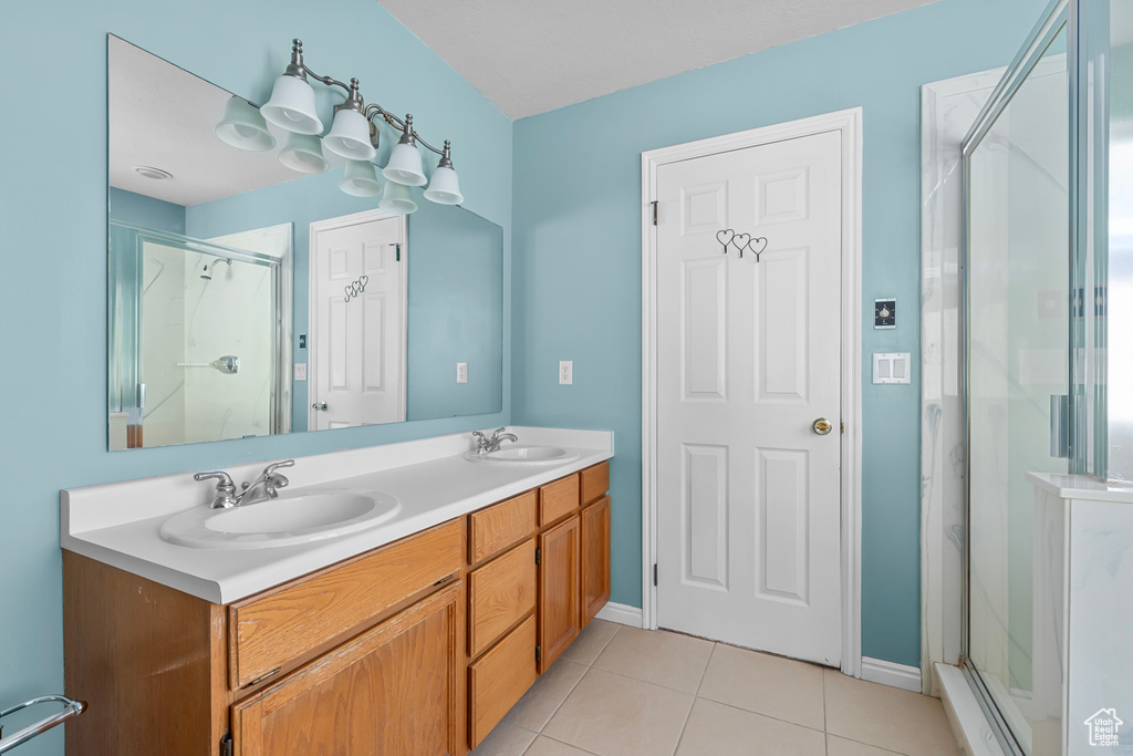 Bathroom with tile patterned floors, a shower stall, and double vanity