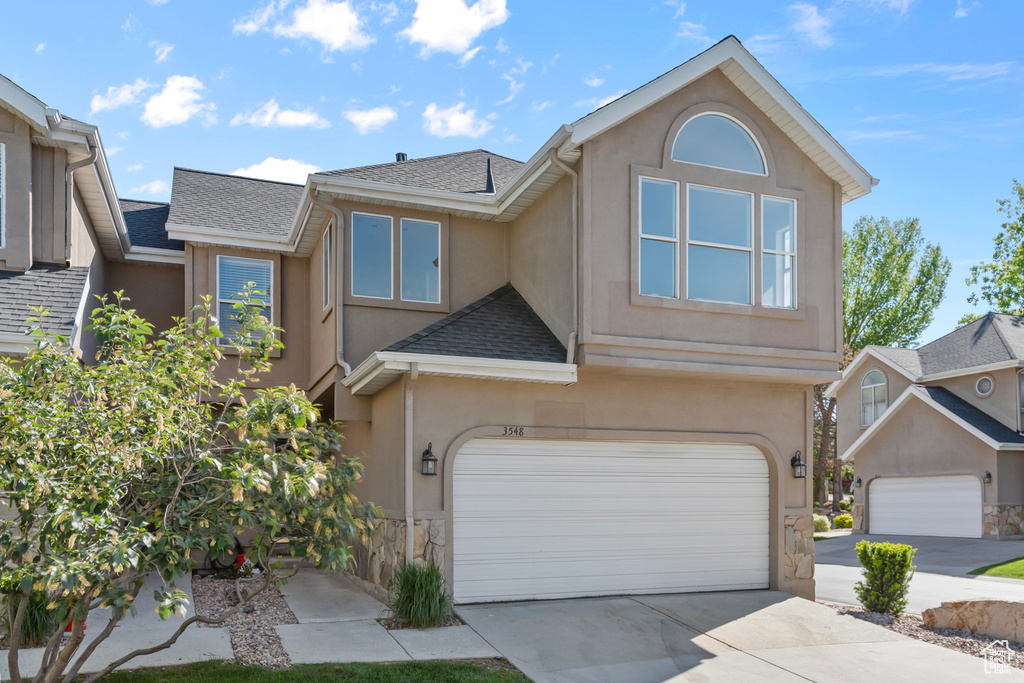 View of front of house featuring stucco siding, an attached garage, and roof with shingles