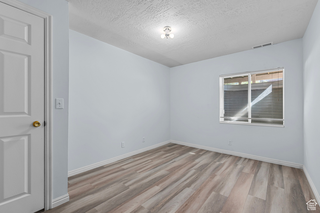 Empty room with light wood-style floors and a textured ceiling
