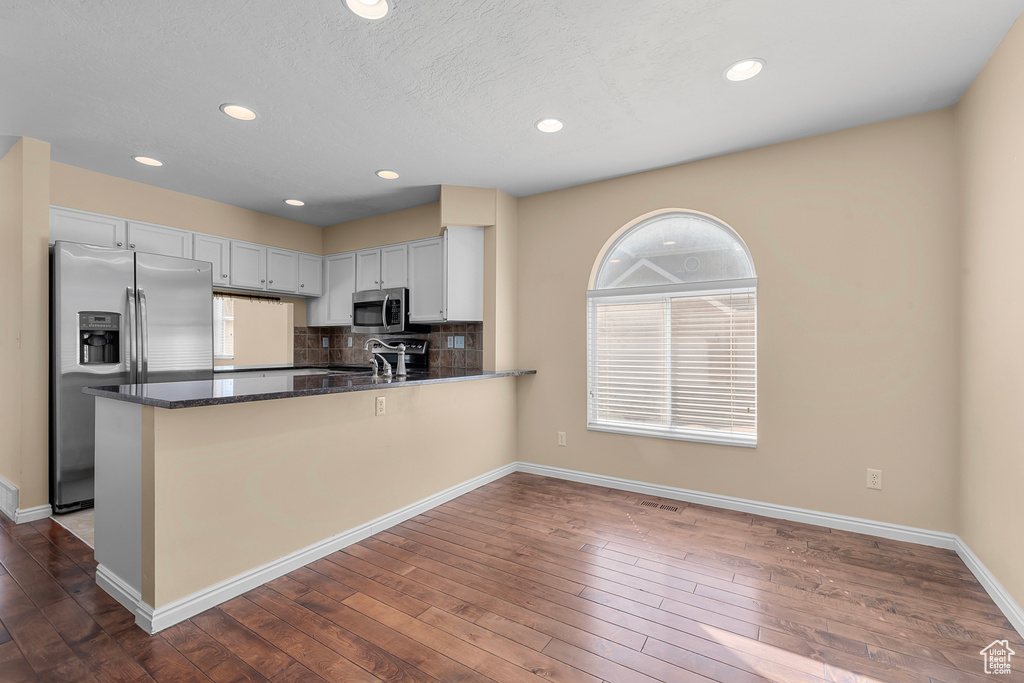 Kitchen with appliances with stainless steel finishes, healthy amount of natural light, tasteful backsplash, dark wood finished floors, and recessed lighting