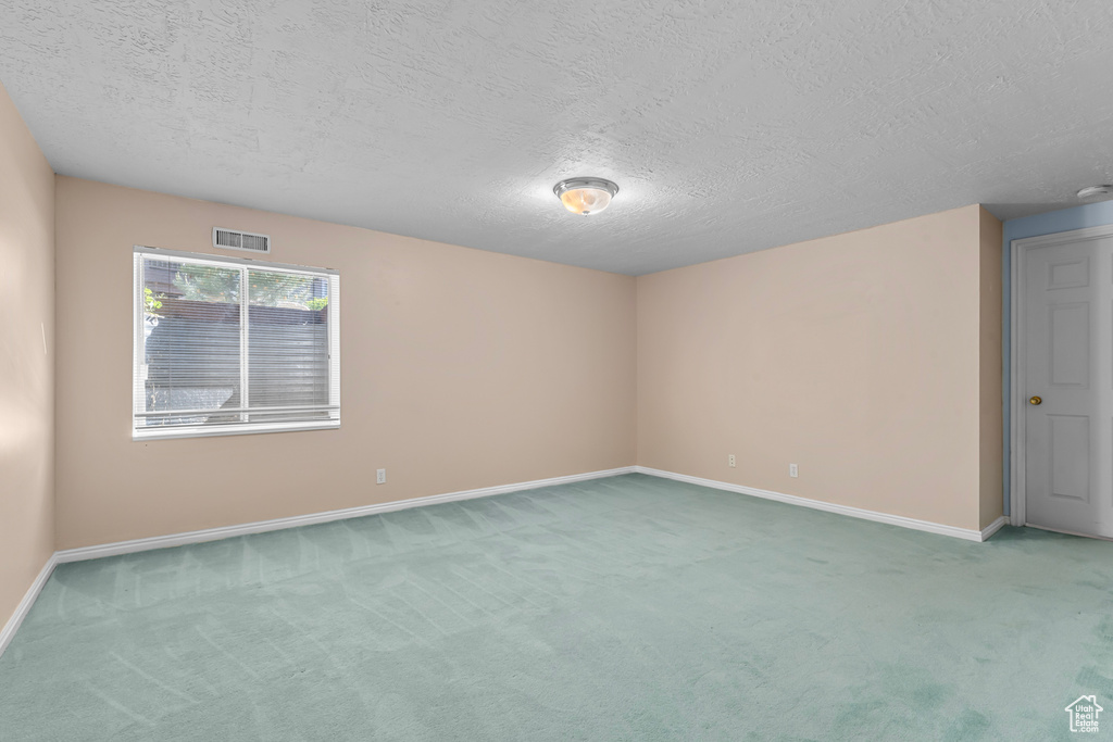 Empty room with carpet floors and a textured ceiling