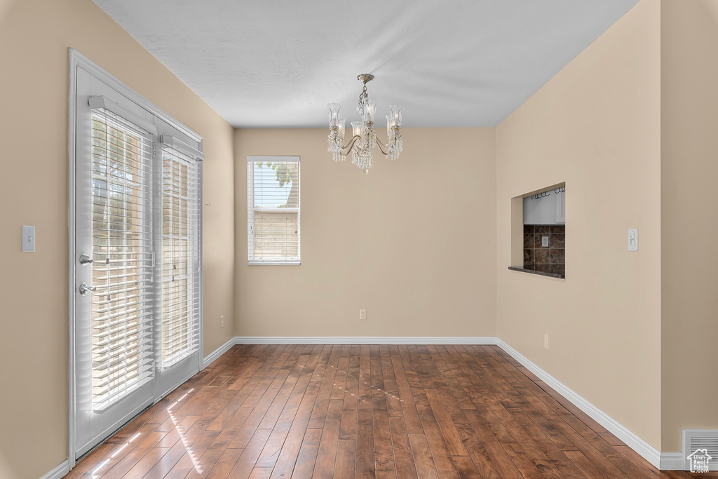 Unfurnished dining area featuring a chandelier and hardwood / wood-style flooring