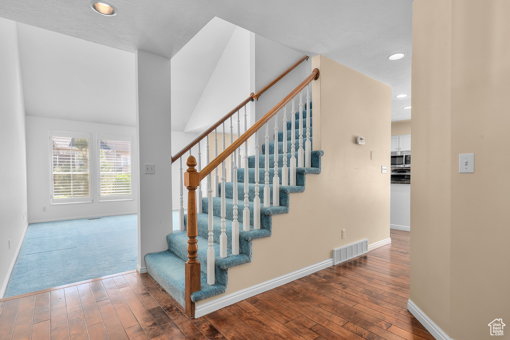 Stairs featuring hardwood / wood-style flooring and recessed lighting