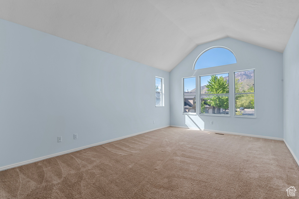Empty room with carpet flooring and vaulted ceiling