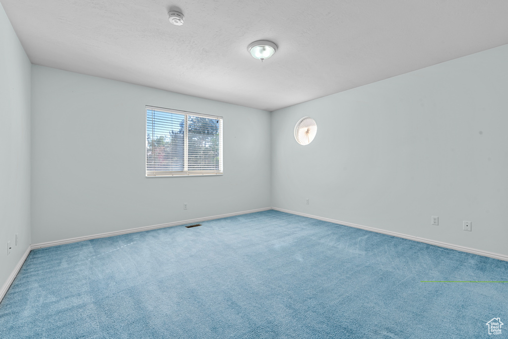 Carpeted empty room with baseboards and a smoke detector