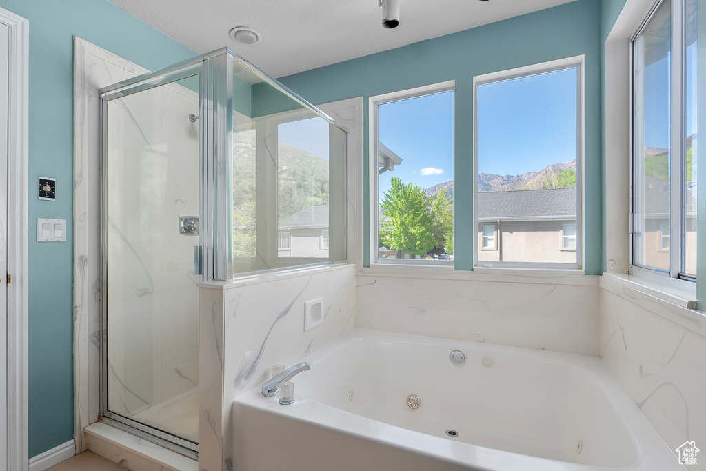 Bathroom featuring a tub with jets, a shower stall, and a mountain view