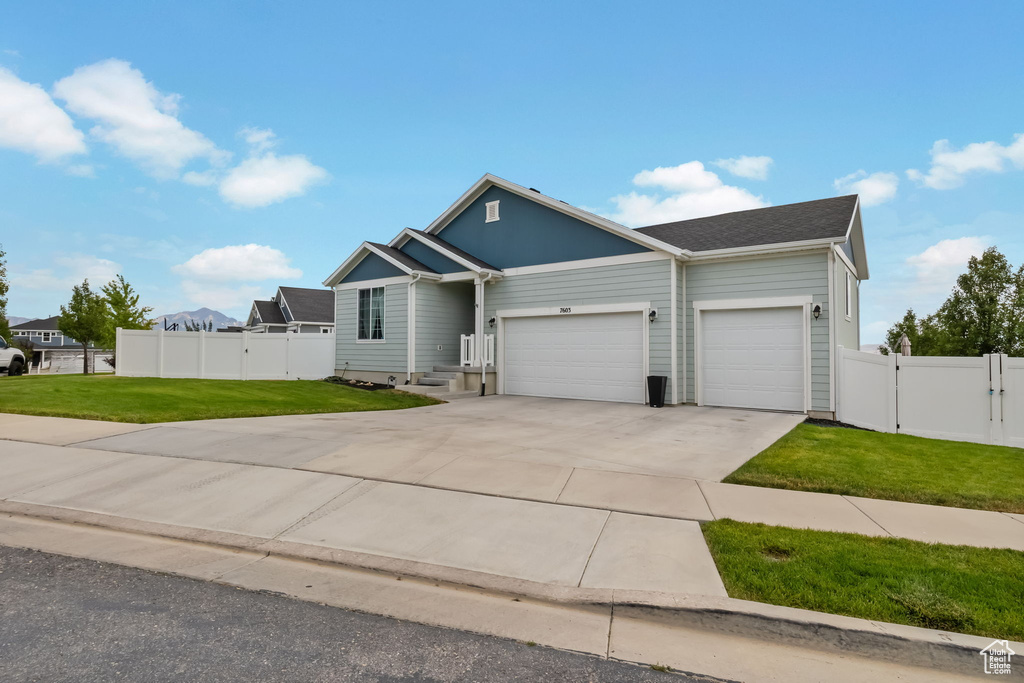 View of front of home with an attached garage, driveway, and a gate