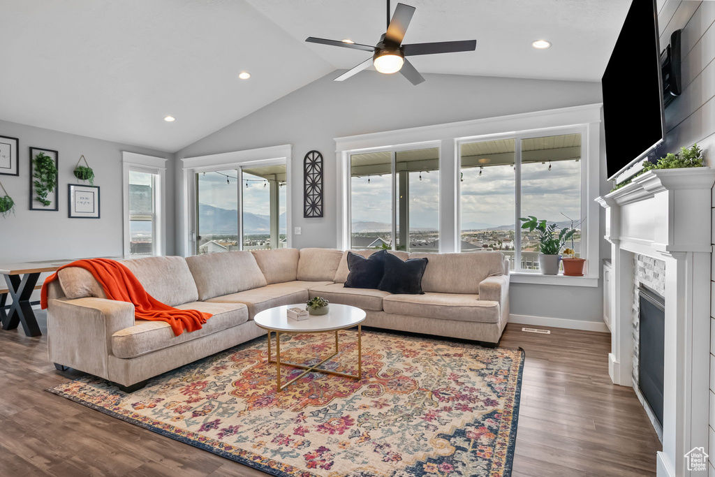 Living area featuring lofted ceiling, a ceiling fan, wood finished floors, recessed lighting, and a fireplace