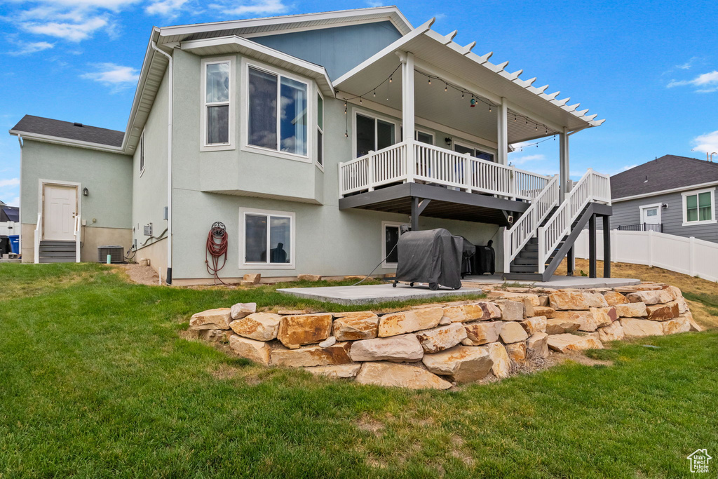 Back of house featuring a patio area, a wooden deck, stucco siding, and stairway