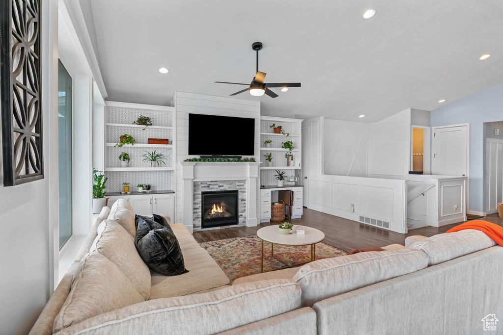 Living room with a ceiling fan, wood finished floors, a glass covered fireplace, recessed lighting, and lofted ceiling