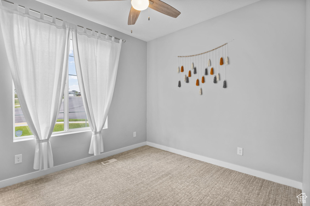 Empty room with ceiling fan and carpet flooring