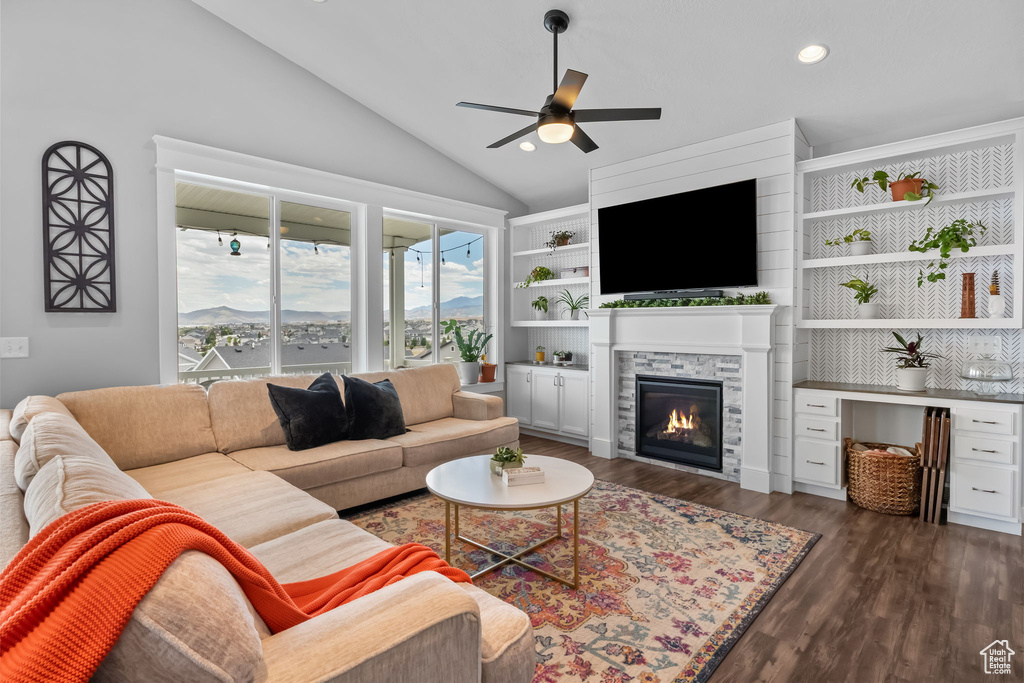 Living room with lofted ceiling, a ceiling fan, dark wood-type flooring, a glass covered fireplace, and recessed lighting