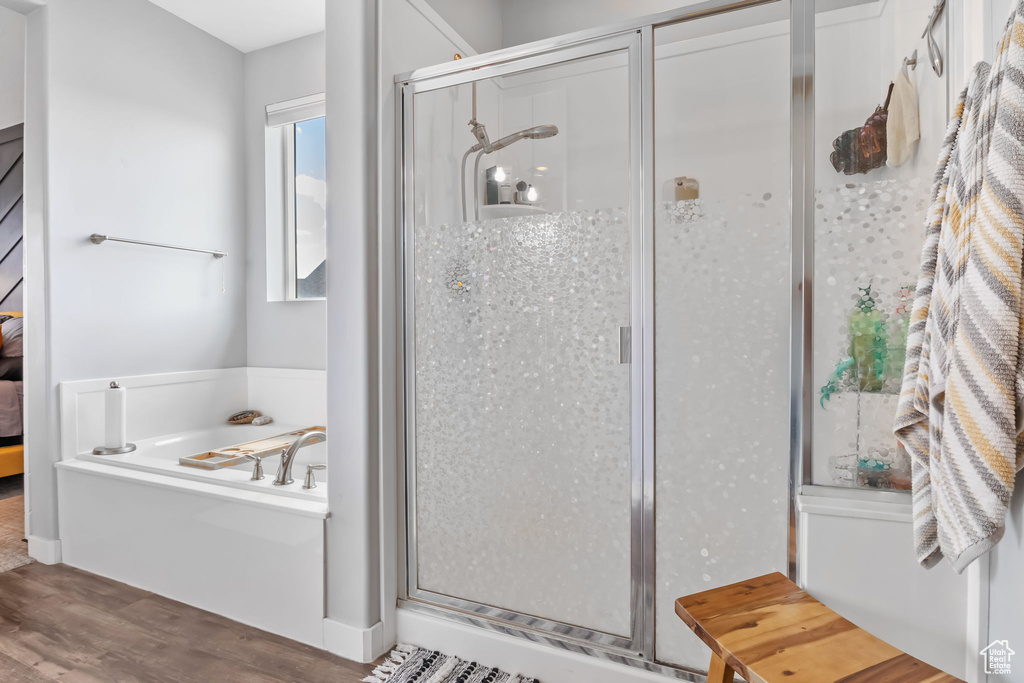 Bathroom with a garden tub, a stall shower, and wood finished floors