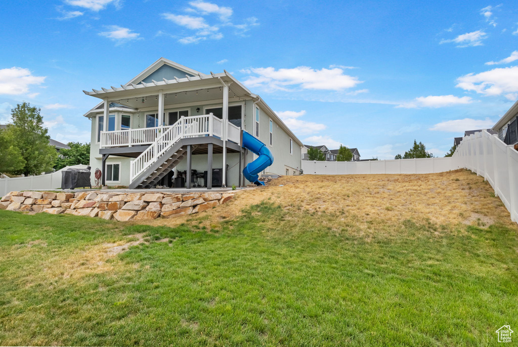 Rear view of house with stairway, a fenced backyard, and a deck