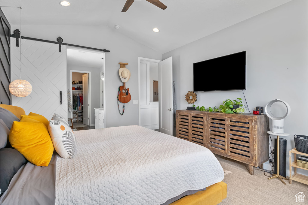 Bedroom with a barn door, vaulted ceiling, recessed lighting, a ceiling fan, and light carpet