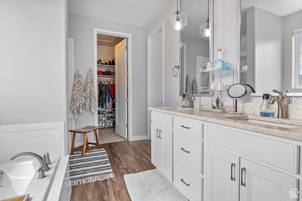 Bathroom with double vanity, wood finished floors, and a walk in closet