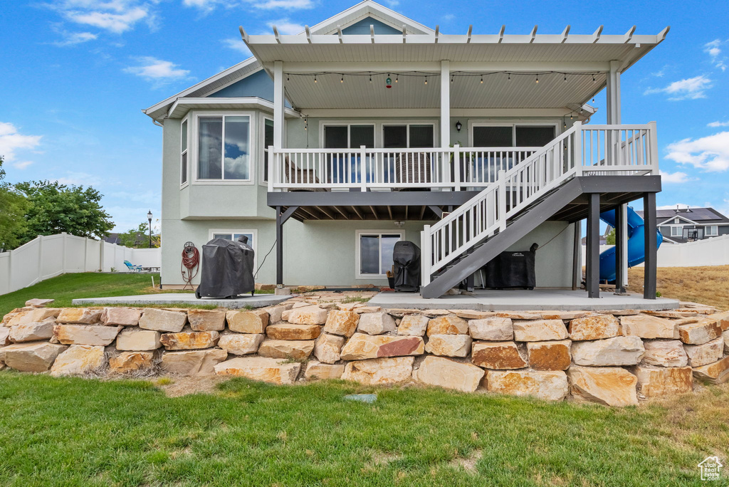 Back of property featuring a wooden deck, a patio area, stucco siding, and stairs