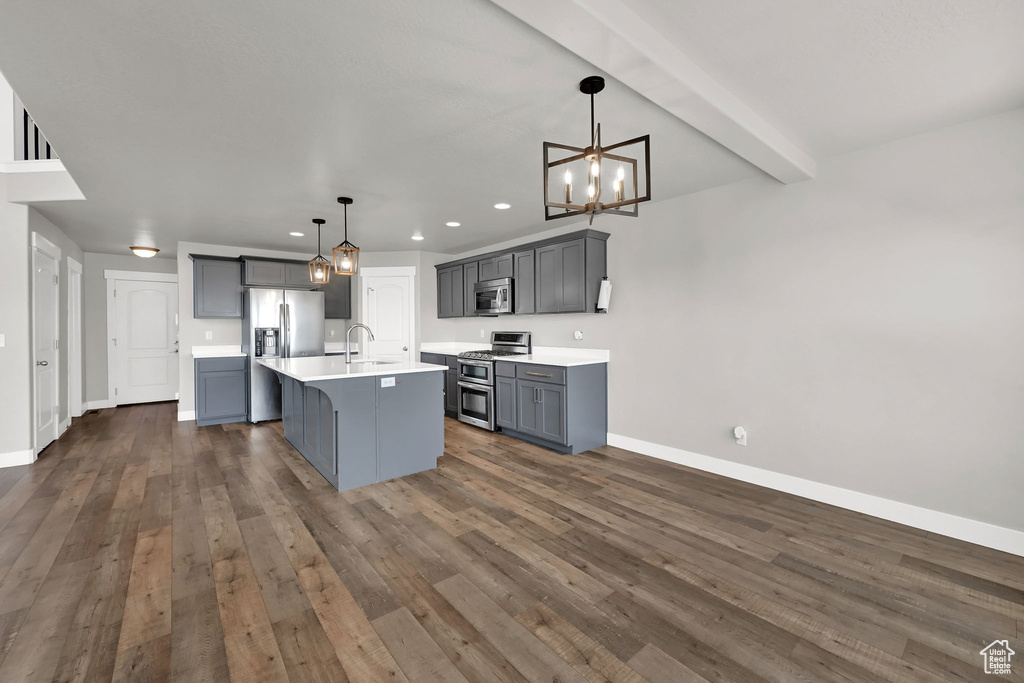 Kitchen featuring stainless steel appliances, gray cabinetry, light countertops, a chandelier, and dark wood-style flooring