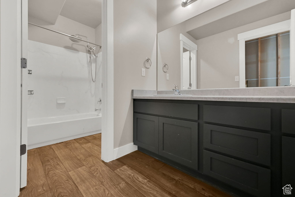 Full bathroom with wood finished floors, double vanity, and bathtub / shower combination