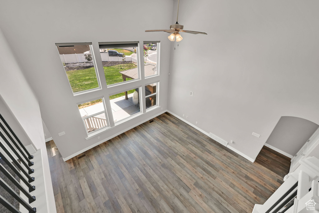 Unfurnished living room featuring a high ceiling, wood finished floors, stairway, and a ceiling fan