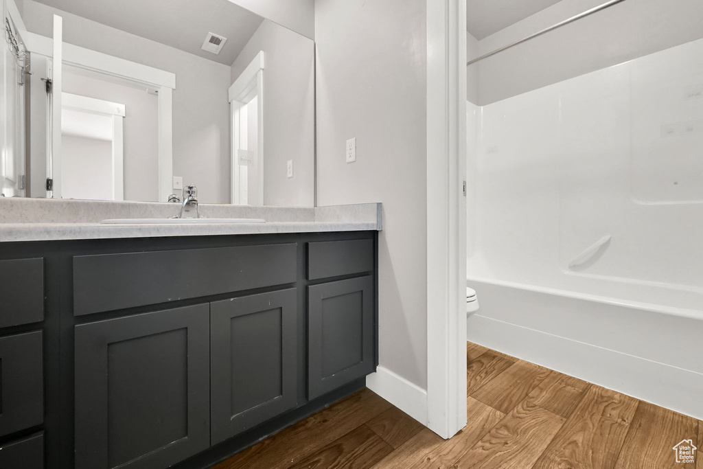 Bathroom with wood finished floors, vanity, and shower / washtub combination