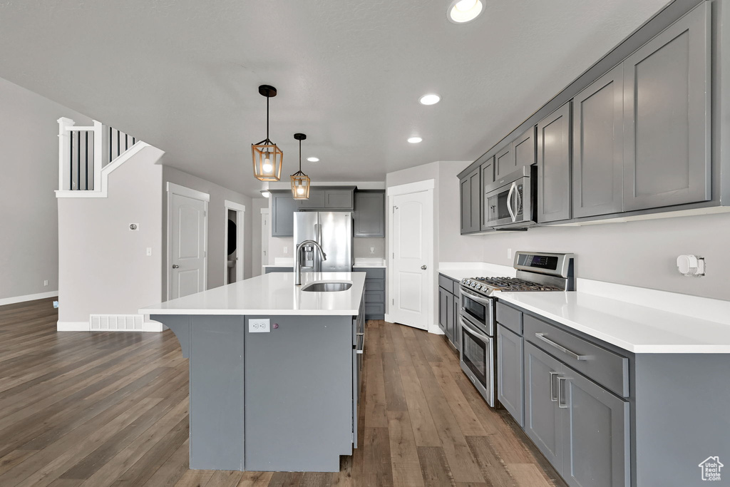 Kitchen with stainless steel appliances, gray cabinetry, recessed lighting, dark wood-style flooring, and light countertops