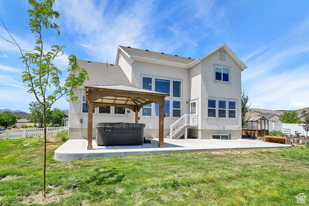 Rear view of property with a hot tub, a patio, a gazebo, a fenced backyard, and stucco siding