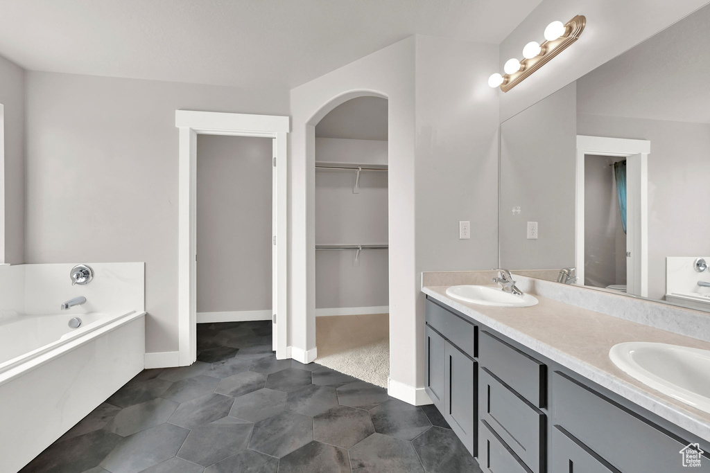 Bathroom with double vanity, a garden tub, and a walk in closet