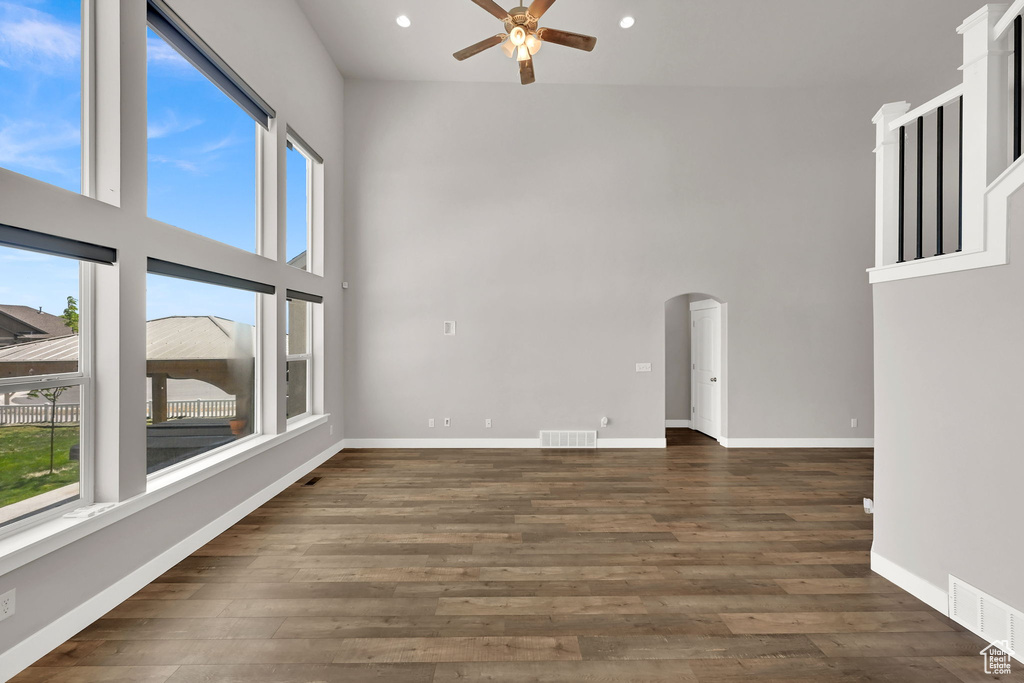 Spare room featuring a towering ceiling, a ceiling fan, arched walkways, recessed lighting, and wood finished floors
