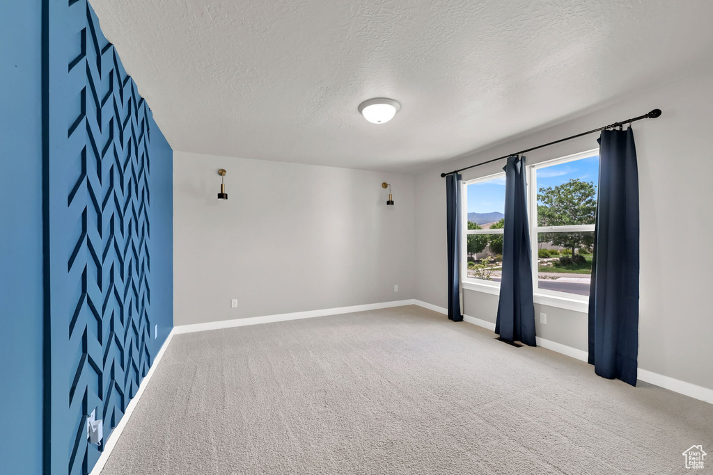 Empty room with a textured ceiling and carpet flooring