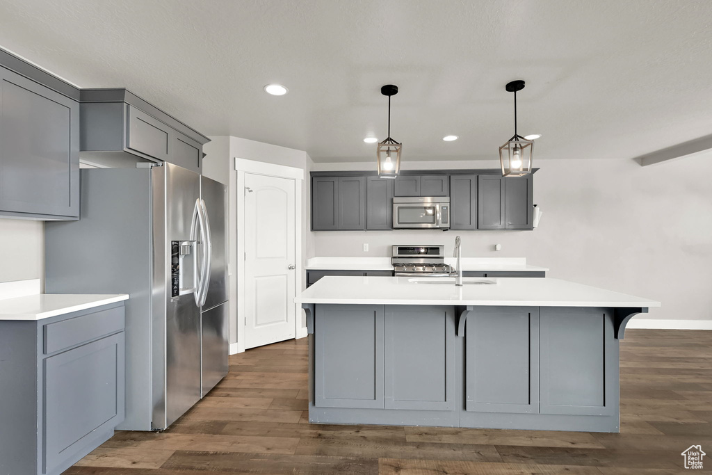 Kitchen featuring appliances with stainless steel finishes, gray cabinetry, recessed lighting, light countertops, and dark wood-type flooring