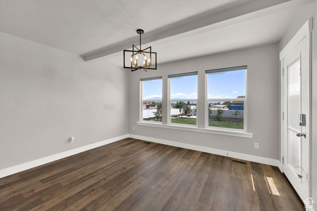 Unfurnished dining area featuring a chandelier, dark wood finished floors, beam ceiling, and a water view