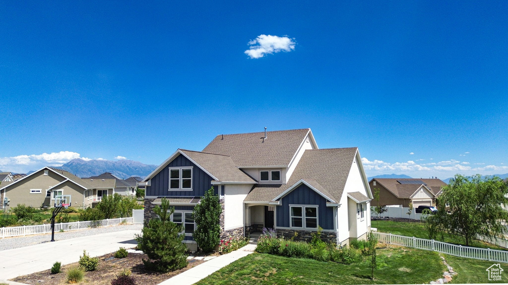View of front of property featuring board and batten siding, stone siding, a shingled roof, and a residential view