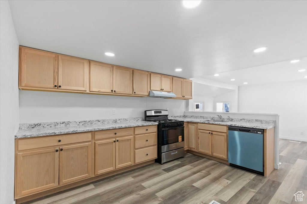 Kitchen featuring dishwasher, gas range, light brown cabinetry, a peninsula, and under cabinet range hood