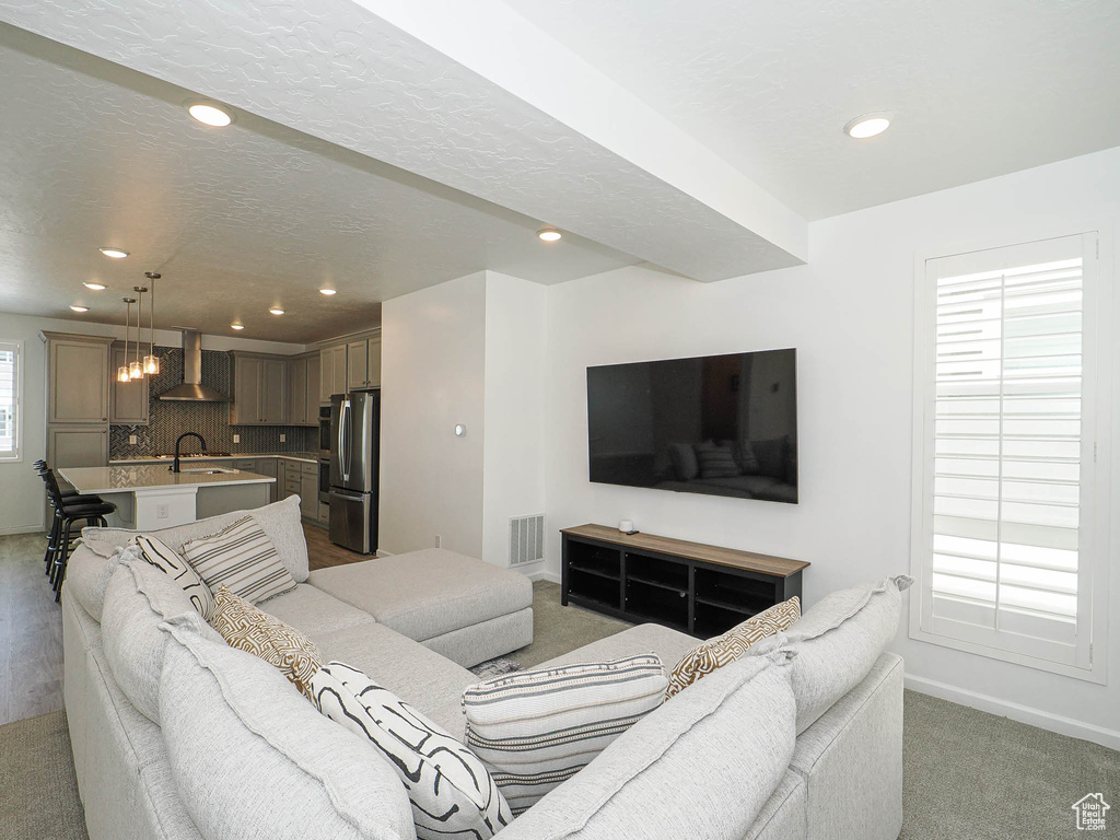 Living area with light carpet and recessed lighting